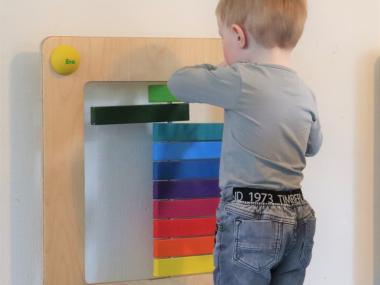 Barn leger med aktivitetslegetøj på væggen